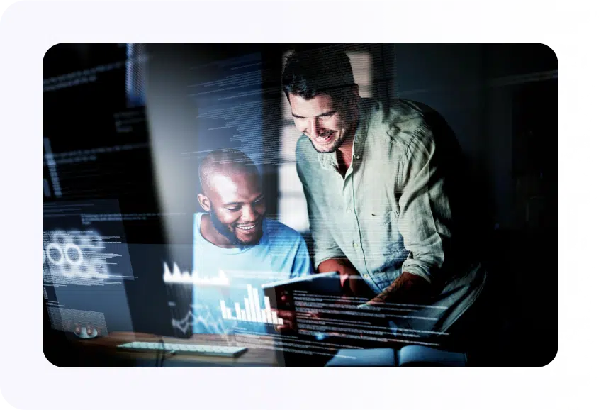 Two men observe a computer screen displaying a text overlay, engaged in discussion and analysis of the content.