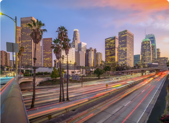 A stunning sunset casts warm hues over the Los Angeles skyline, highlighting the city's iconic architecture and silhouette.